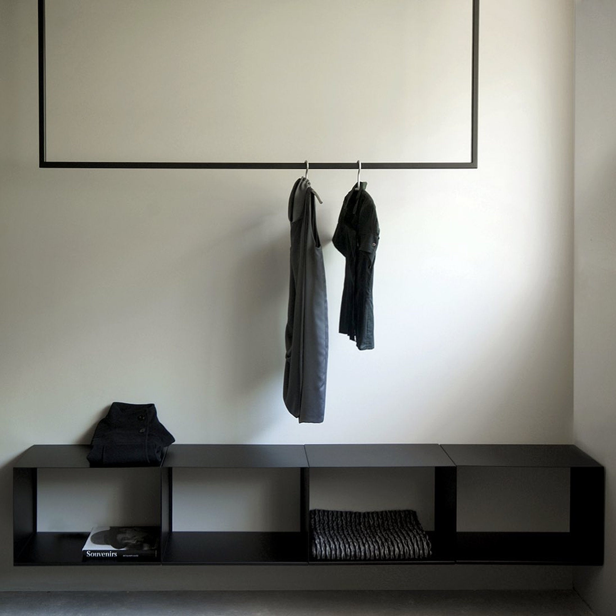 Khao xam nero, mensola contenitore a parete con vani aperti; sopra, appendiabiti con capi.