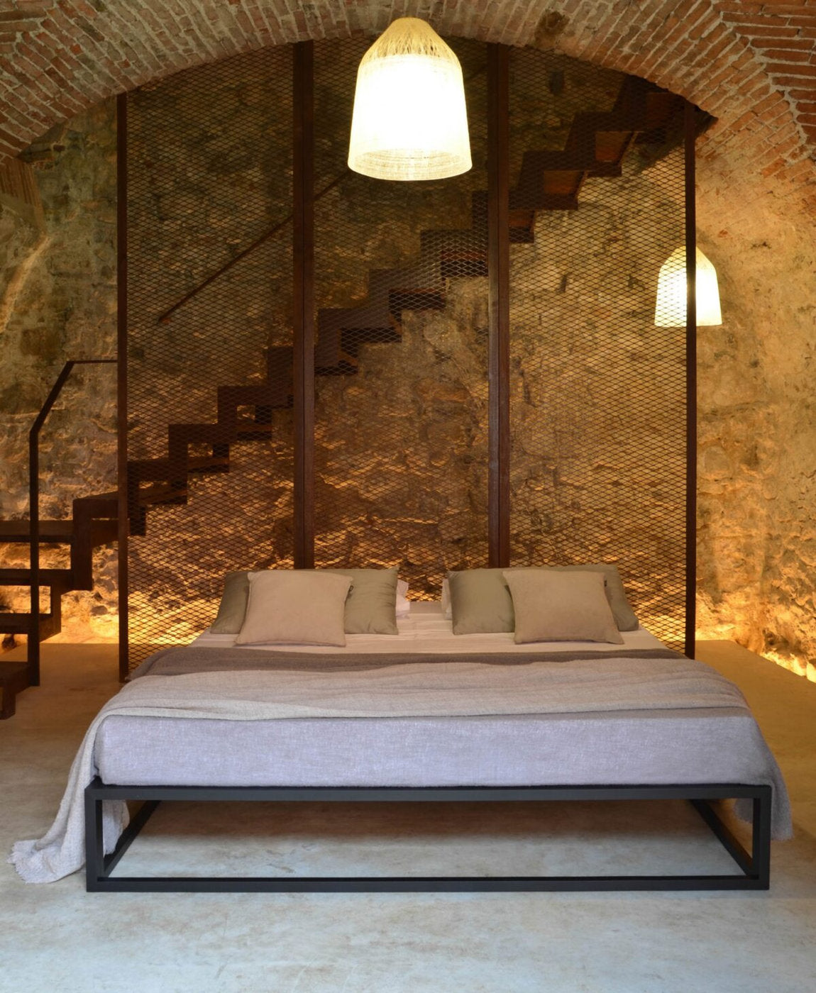 Letto Asha Basic 3.0 in ambientazione con parete in pietra e luce calda radente