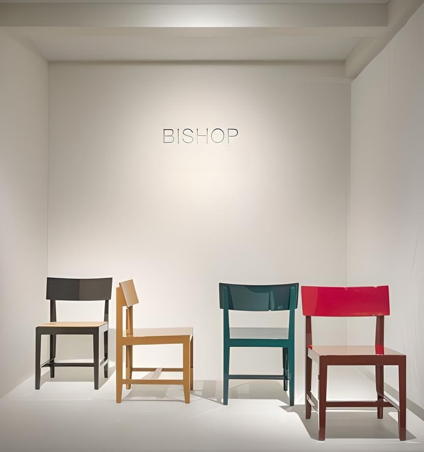 Vista dell’allestimento Bishop per Magis durante il Salone del Mobile 2025, con quattro sedie in acciaio laccato in diversi colori, esposte su pedana bianca.