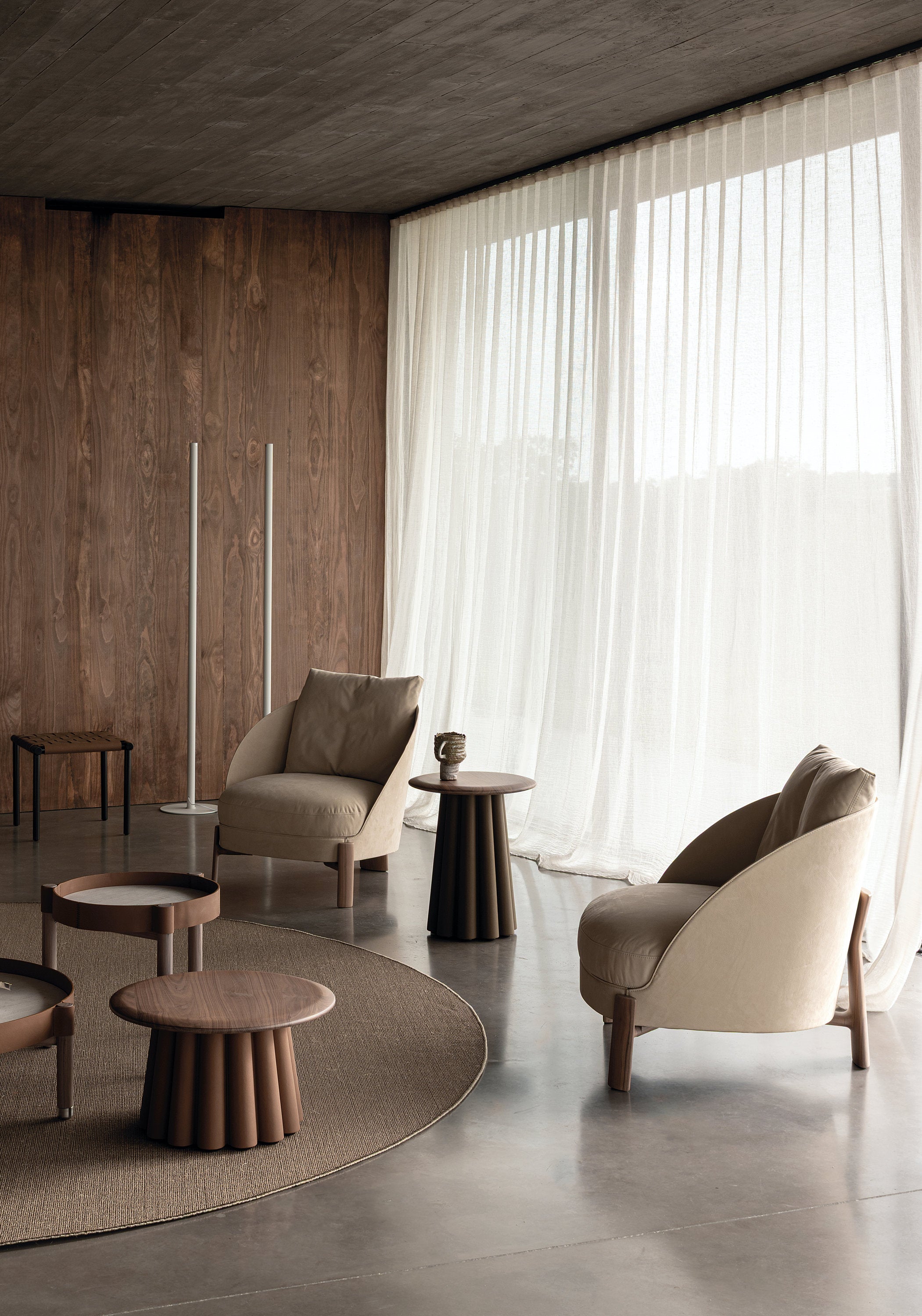 Due poltrone Catarina Cierre1972 inserite in uno spazio living con pavimento in cemento e parete in legno naturale