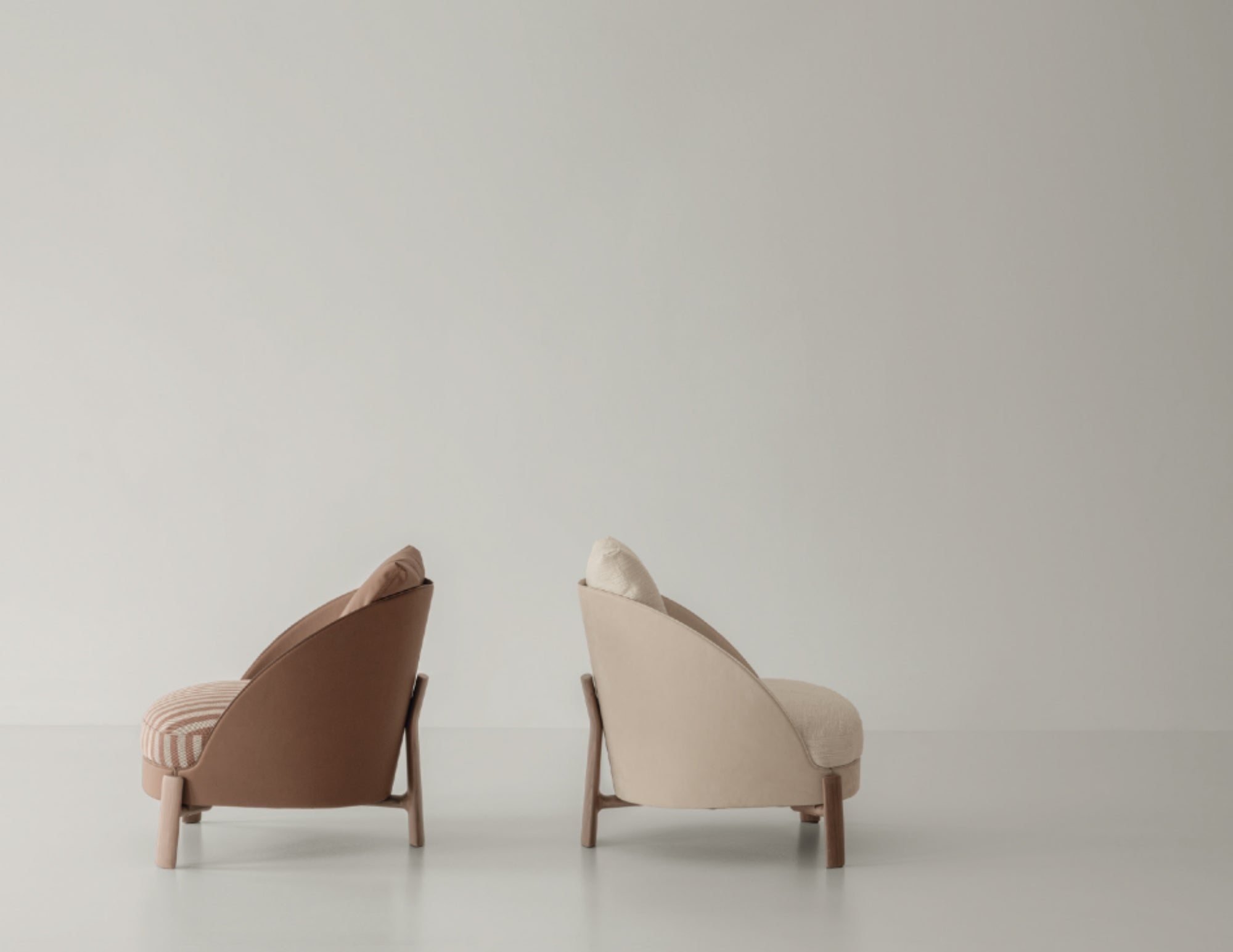 Vista di profilo di due poltrone Catarina di Cierre1972 con rivestimenti differenti, su fondo neutro