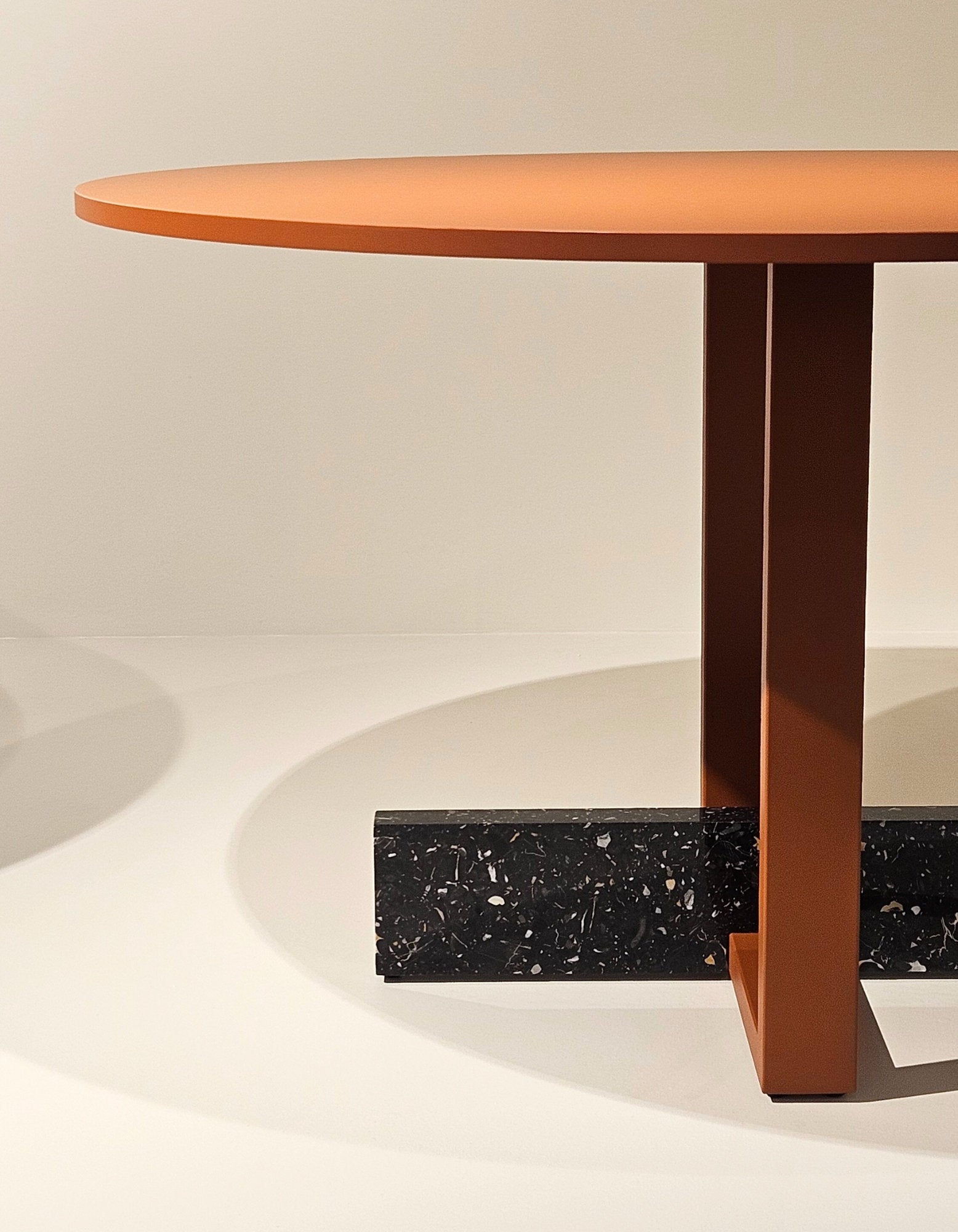 Dettaglio della base del tavolo Pied-à-Terre di Magis con struttura arancio e contrappeso in marmo riciclato nero