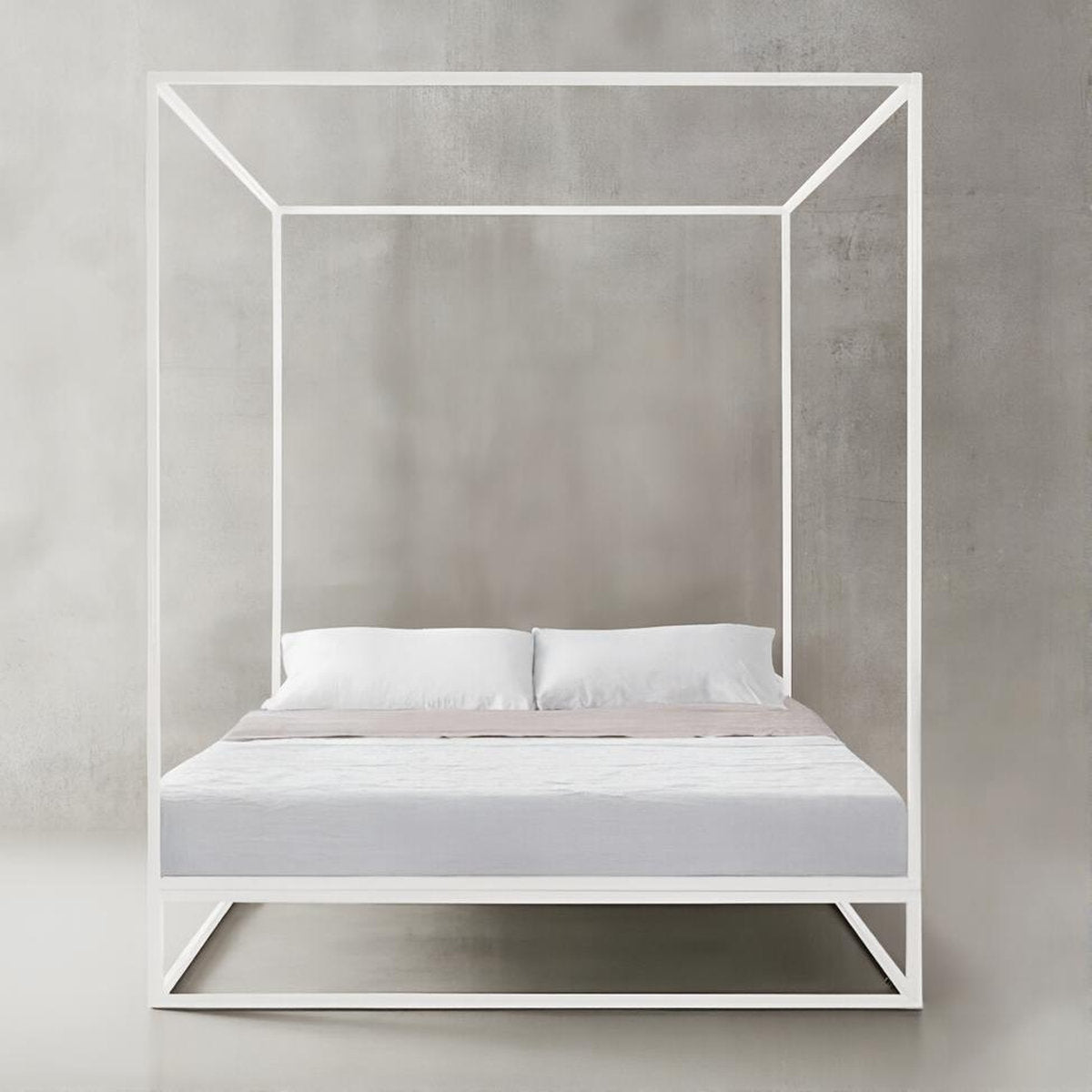 Letto Asha Baldaquin bianco fotografato frontalmente contro parete in cemento grigio chiaro