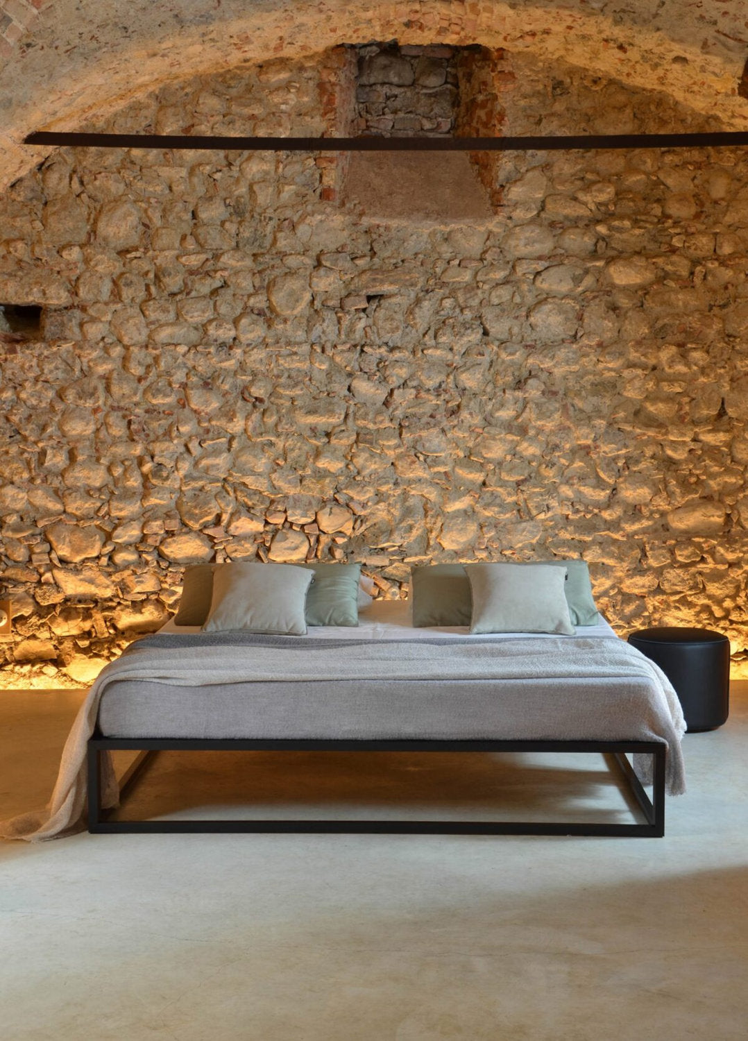 Letto Asha Basic 3.0 con struttura nera in ferro e sfondo in pietra rustica illuminata