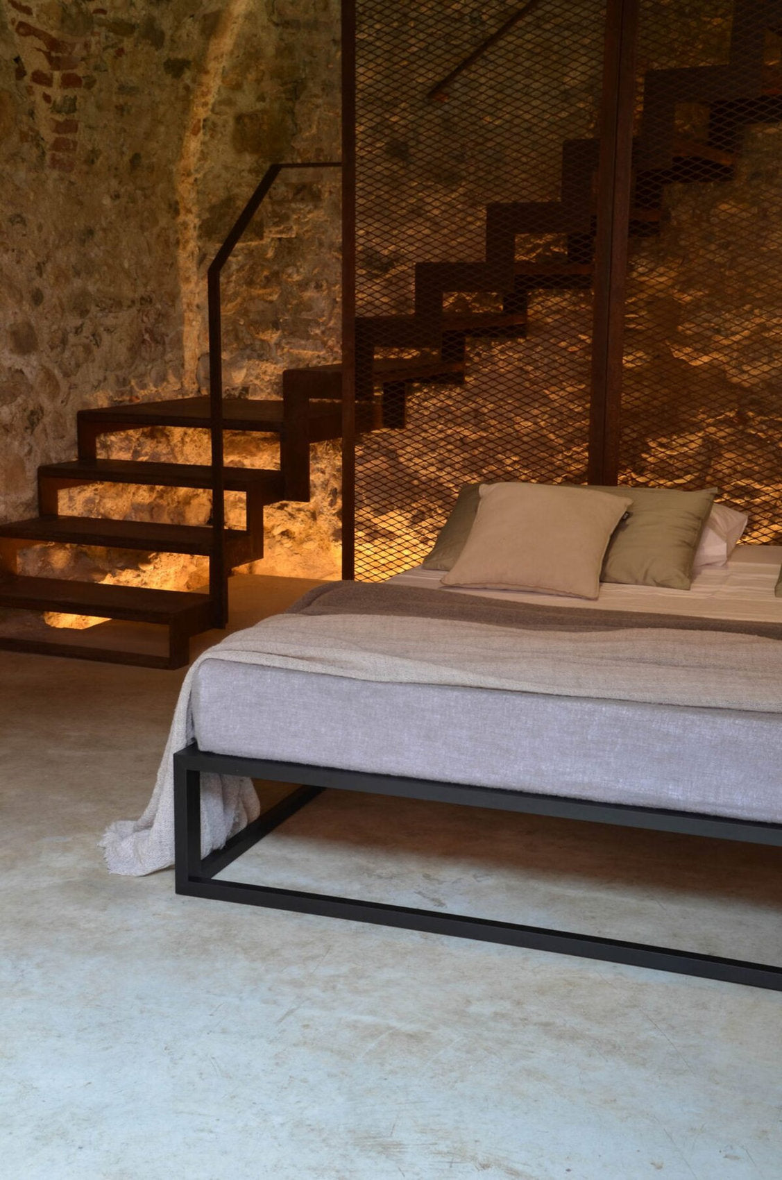 Letto Asha Basic 3.0 con struttura minimal e parete in pietra, illuminazione soffusa