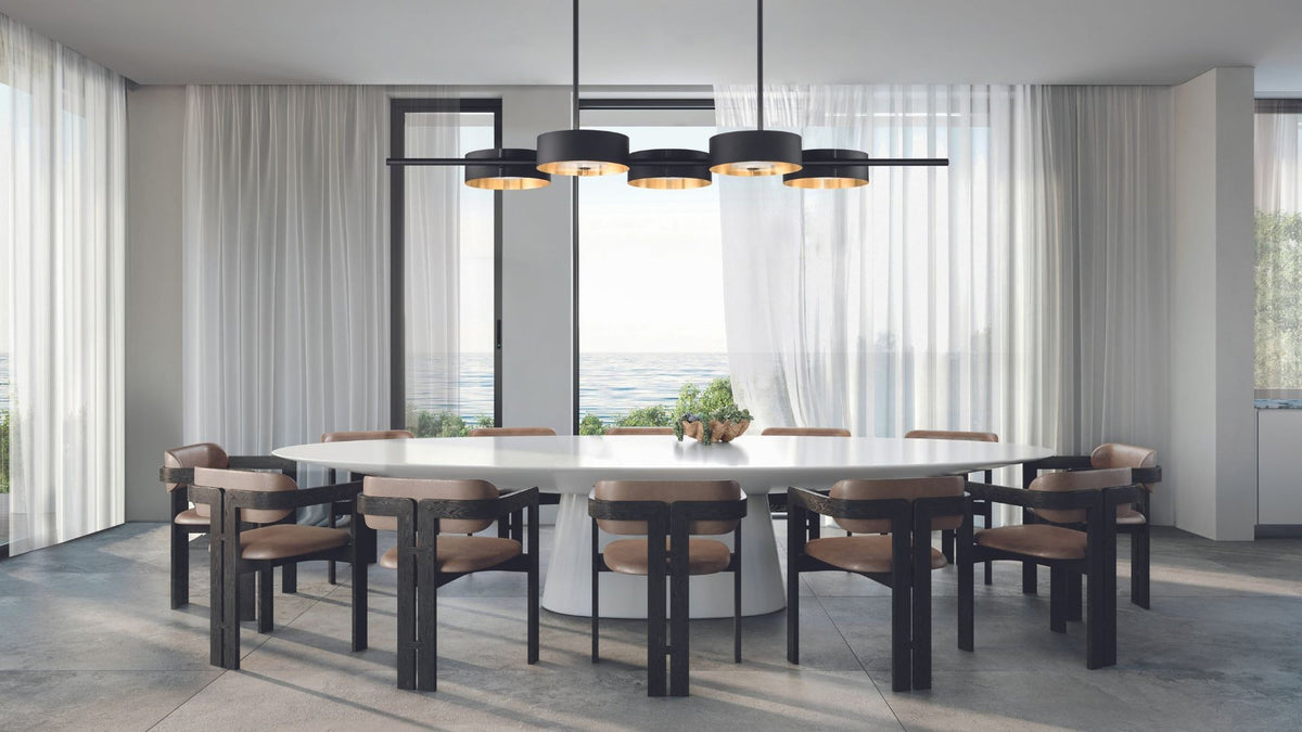 Lampada a sospensione Sound BIL5 Masiero con 5 elementi circolari neri e interni dorati sopra un tavolo bianco ovale.