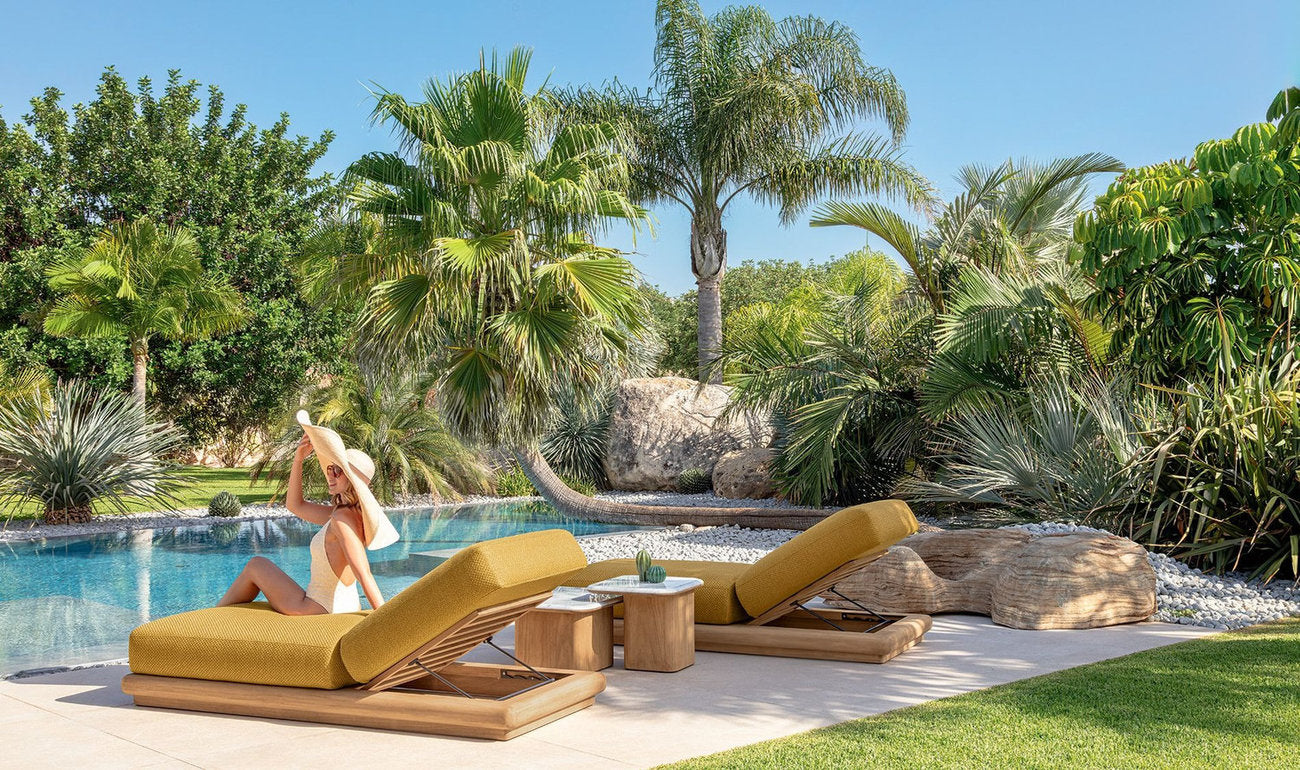 Lettini prendisole Talenti Itaca bordo piscina con cuscini ocra in giardino tropicale