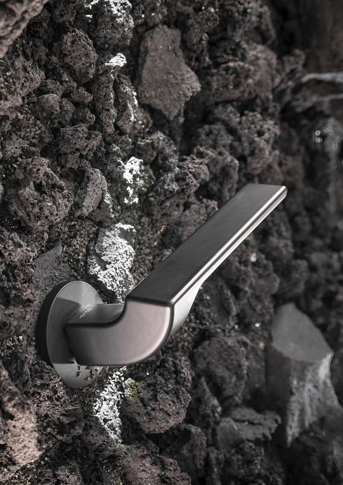 Maniglia Nur Ento in ottone su parete materica, design Lorenzo Palmeri per porte interne