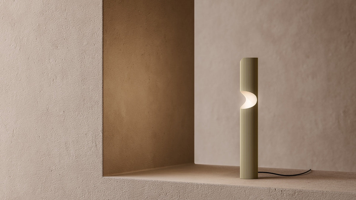 Lampada da tavolo LED Na-ar TL di Masiero in ottone rigato dorato, con diffusore luminoso curvo, su mensola in nicchia.