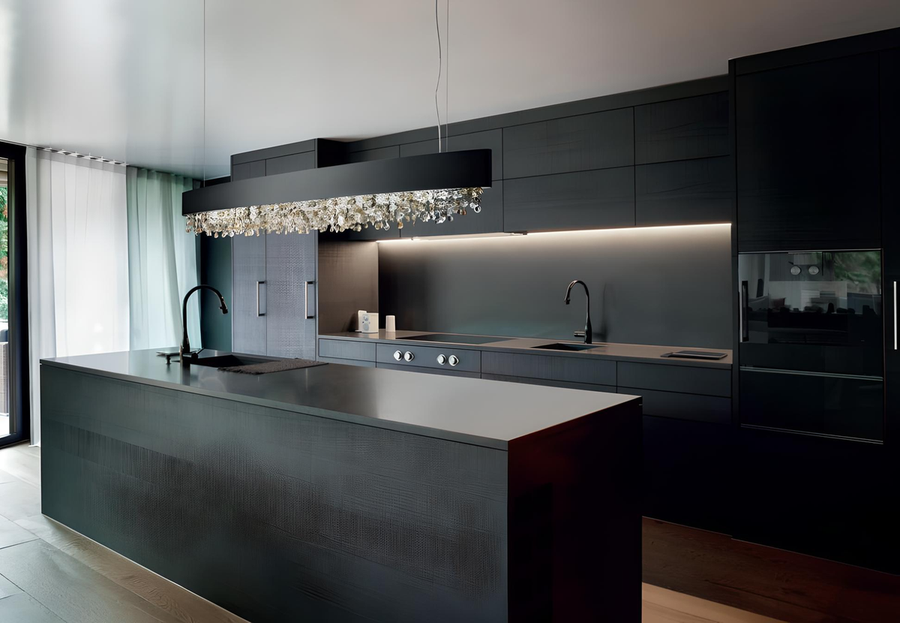 Lampada Olà di Masiero in versione nera opaca con pendagli in vetro trasparente, installata sopra una cucina total black con isola centrale.
