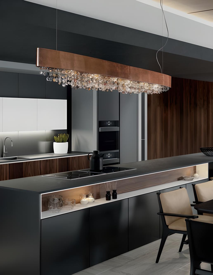 Lampada Olà di Masiero in versione ramata con pendagli in vetro, sospesa sopra una cucina con isola centrale e arredi minimal.