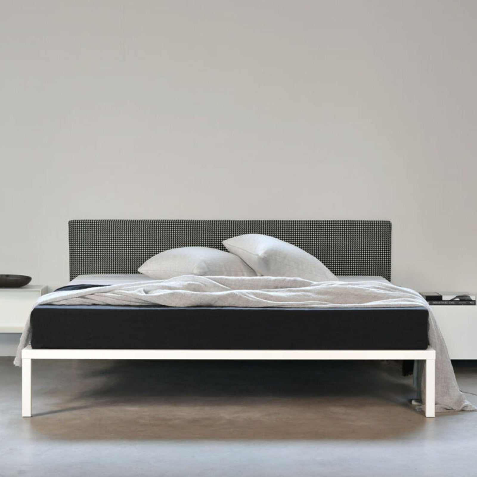 Letto X One con testata Xam in tessuto nero e struttura in acciaio verniciato, ambientazione minimal a Milano
