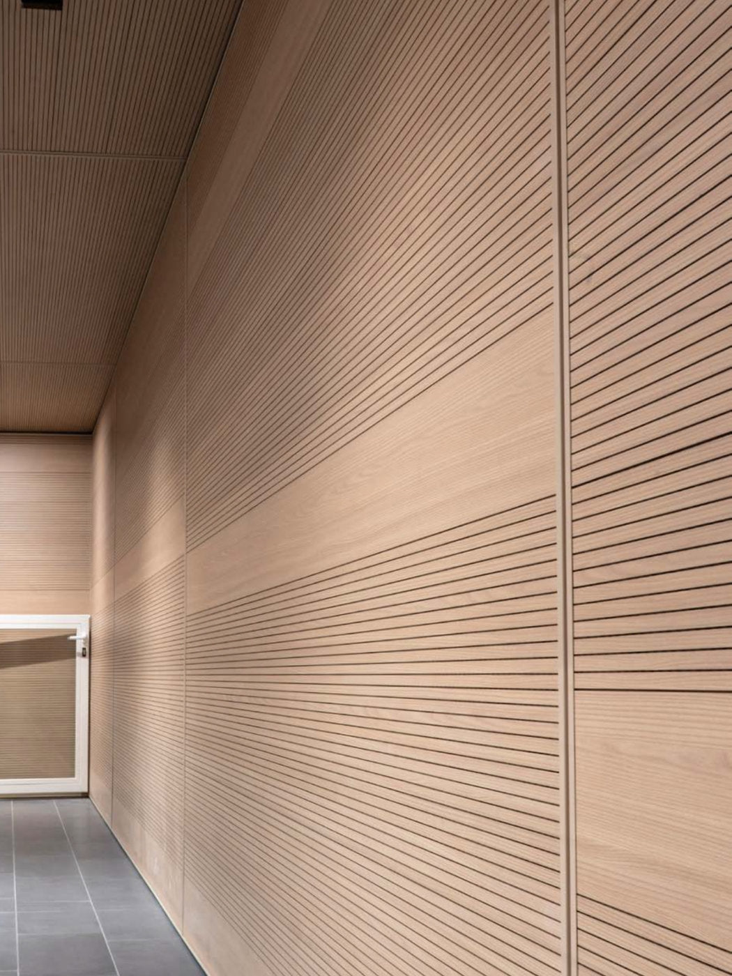 Rivestimenti fonoassorbenti a parete e soffitto in legno chiaro in spazio pubblico auditorium