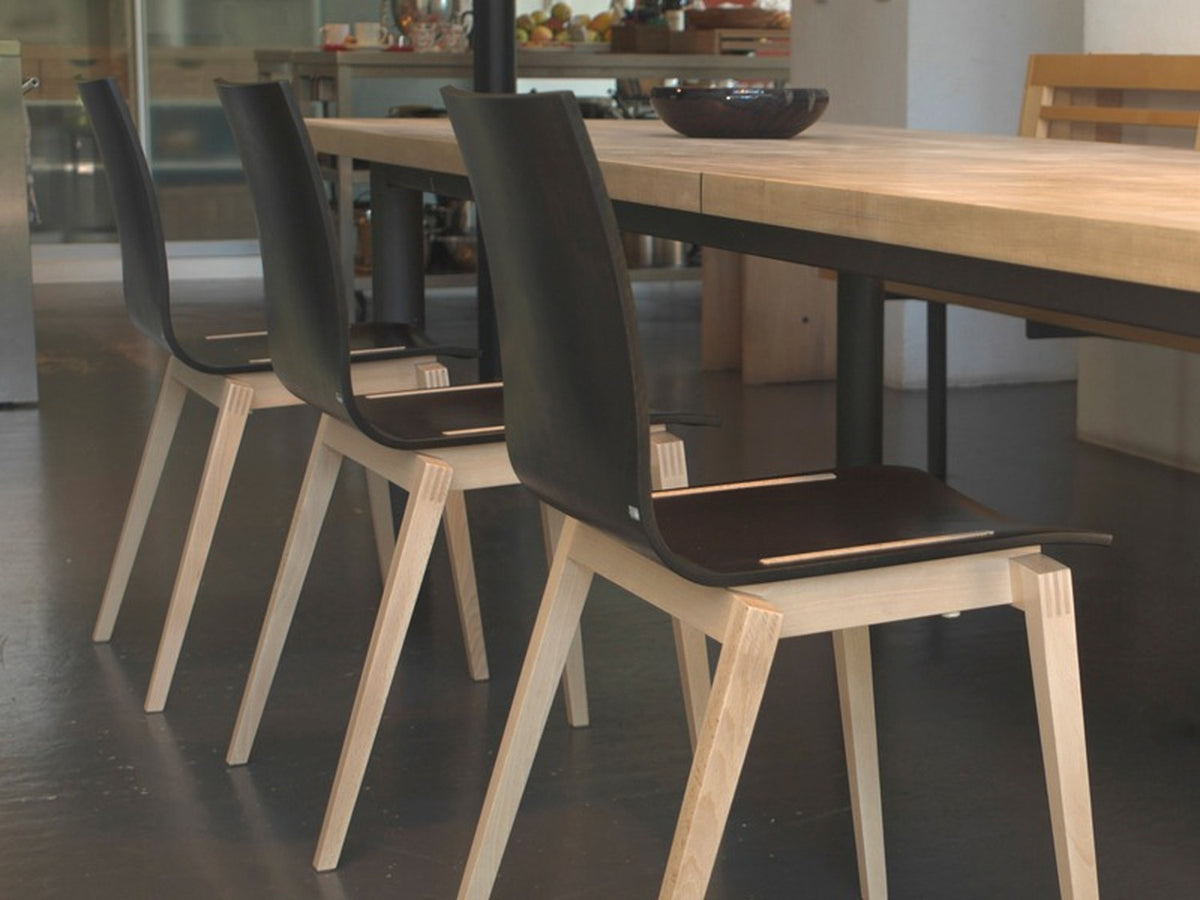 Sedie Stockholm TON in legno chiaro con seduta scura, abbinate a tavolo da pranzo in ambiente contemporaneo.