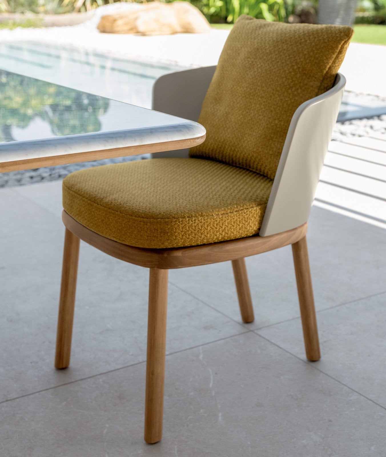Sedia pranzo outdoor Itaca Talenti in legno Accoya con cuscino ocra, accanto a tavolo da esterno