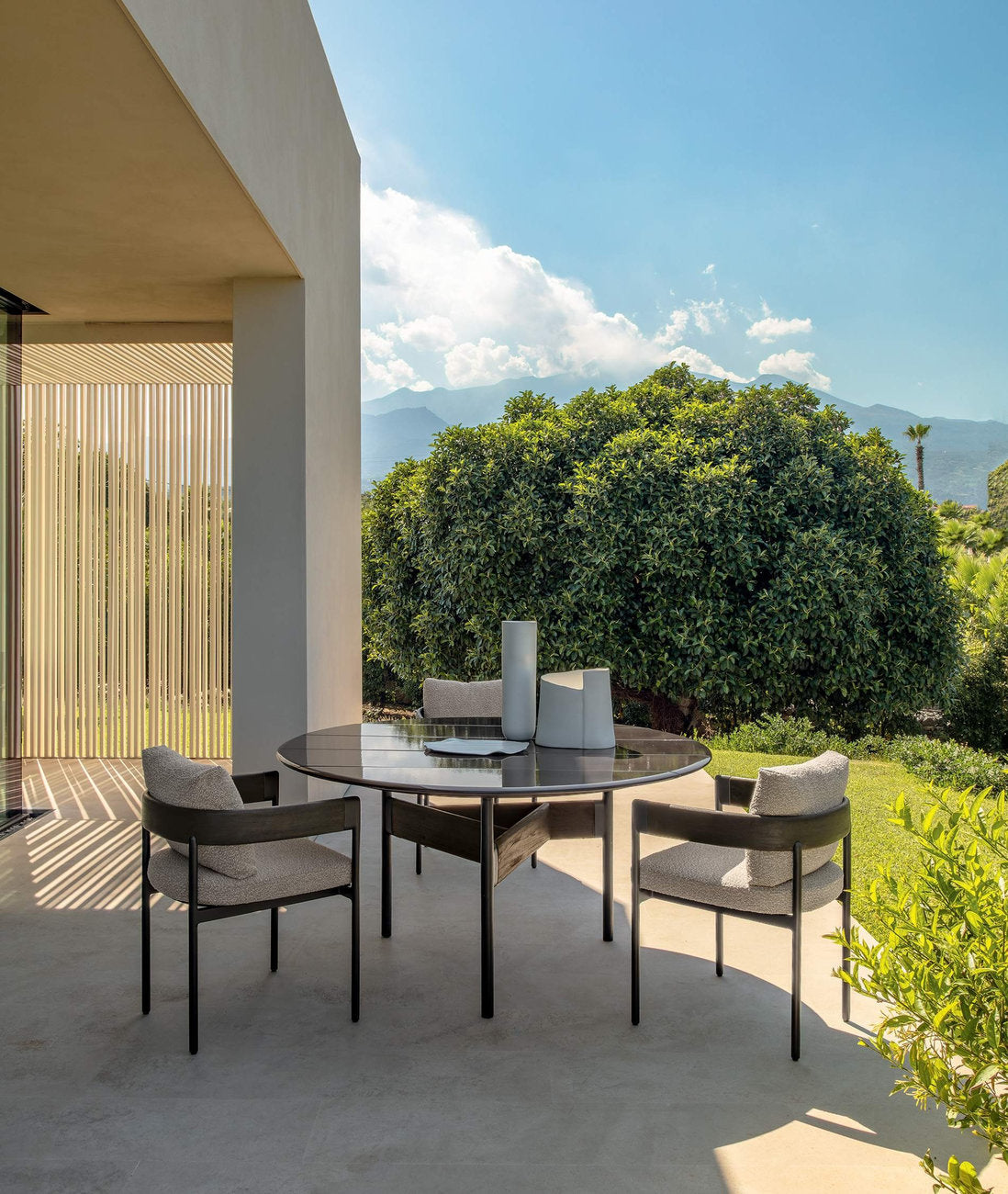 Sedie outdoor Flow Talenti attorno a tavolo rotondo in alluminio e teak su terrazza