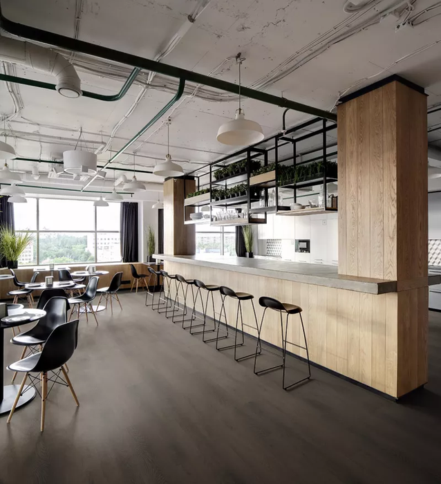 Spazio ristorante con pavimento vinilico effetto legno scuro StarKR Rovere Ossidato, arredato con sedute nere e banco in legno chiaro