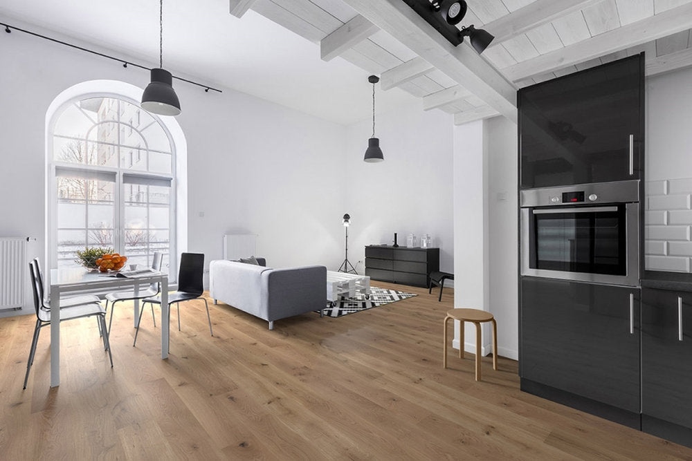 Zona giorno luminosa con parquet in Rovere Maser della collezione Palladio di Skema, posa a correre e arredi moderni su fondo bianco.