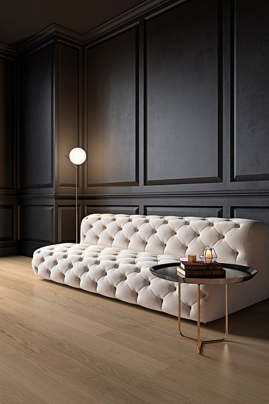 Ambiente elegante con pareti scure e divano capitonné, pavimento in Rovere Venezia della collezione Palladio Skema, posa regolare.