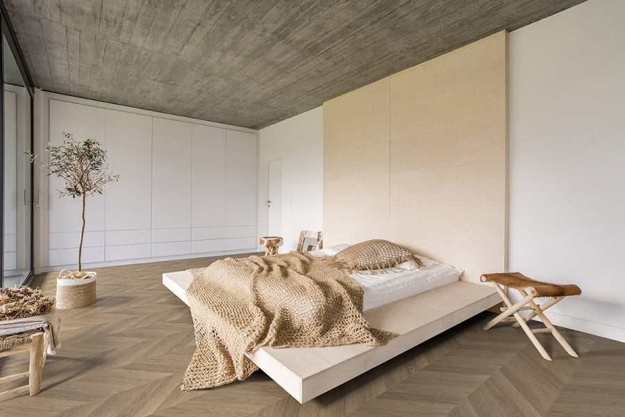 Camera minimalista con pavimento vinilico SPC effetto legno a spina francese StarKs Skema, parete chiara e letto in legno basso