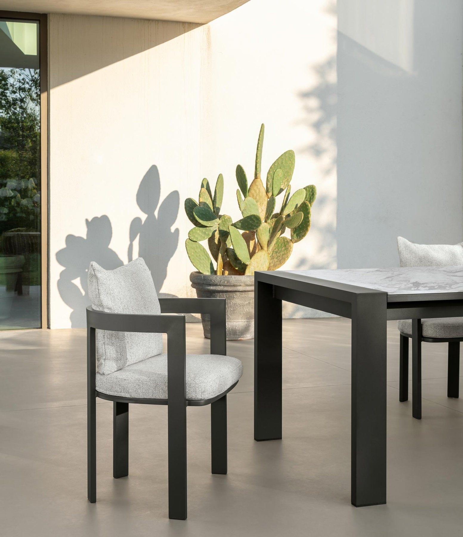 Dettaglio tavolo Argo Alu Talenti in alluminio scuro con sedie outdoor imbottite su patio