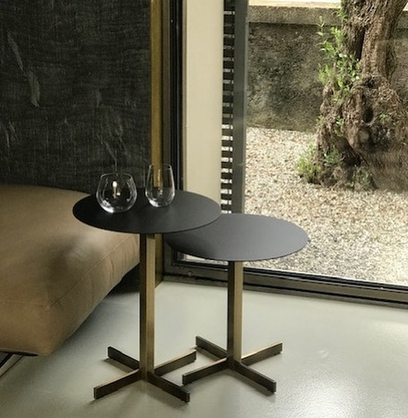 Coppia di tavolini Xo Brass con struttura in ottone e piano nero, vicino a vetrata con vista su giardino