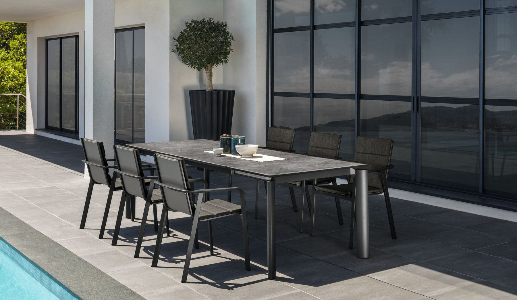 Tavolo da giardino Milo Talenti con piano scuro e sedie coordinate in terrazza a bordo piscina
