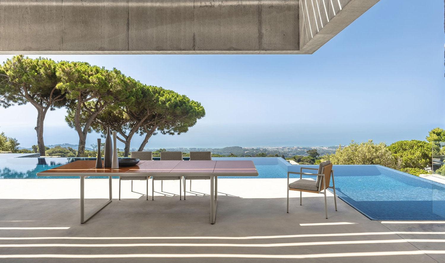 Tavolo da pranzo outdoor Tressé Talenti in pietra lavica su terrazza con piscina e vista mare