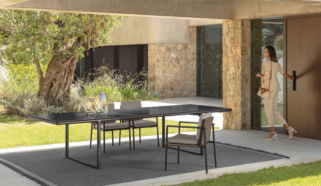 Tavolo outdoor Tressé Talenti con piano scuro in pietra lavica in zona pranzo esterna coperta
