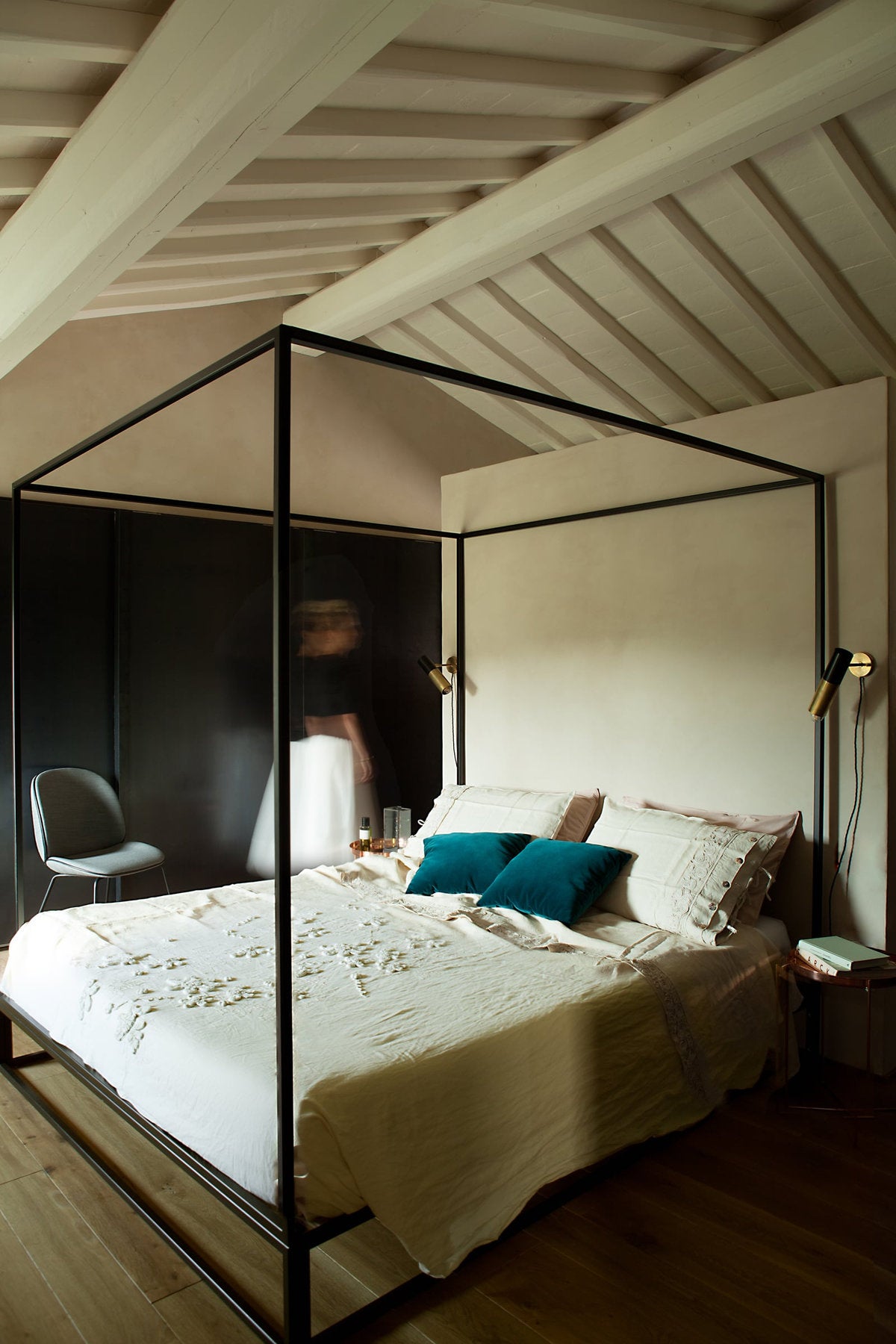 Letto a baldacchino Xam Asha in metallo nero in una camera con travi a vista e pareti neutre 
