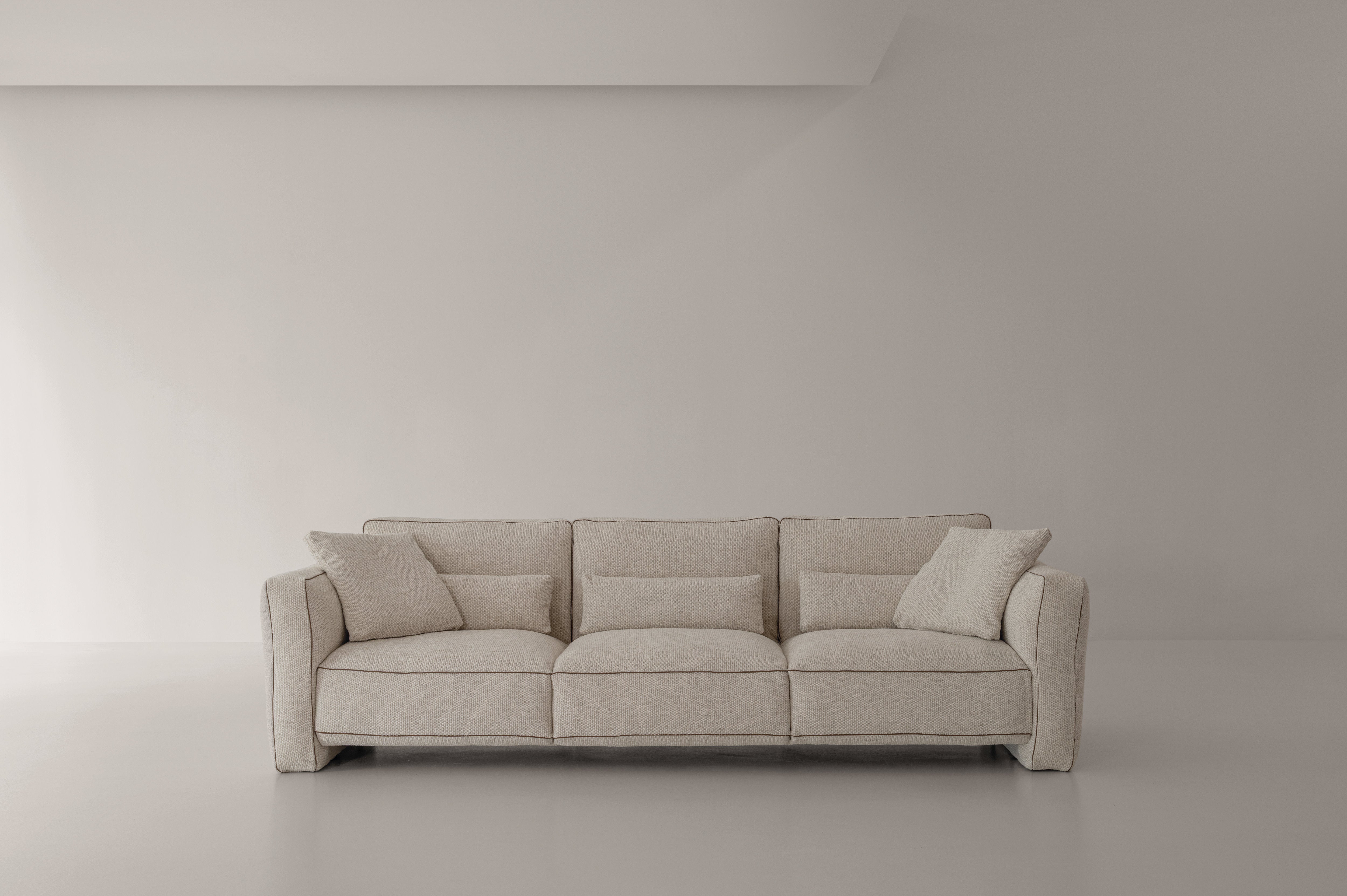Divano modulare Loden Cierre1972 in tessuto chiaro, tre posti, con cuscini di diverse dimensioni, su fondo minimalista beige

