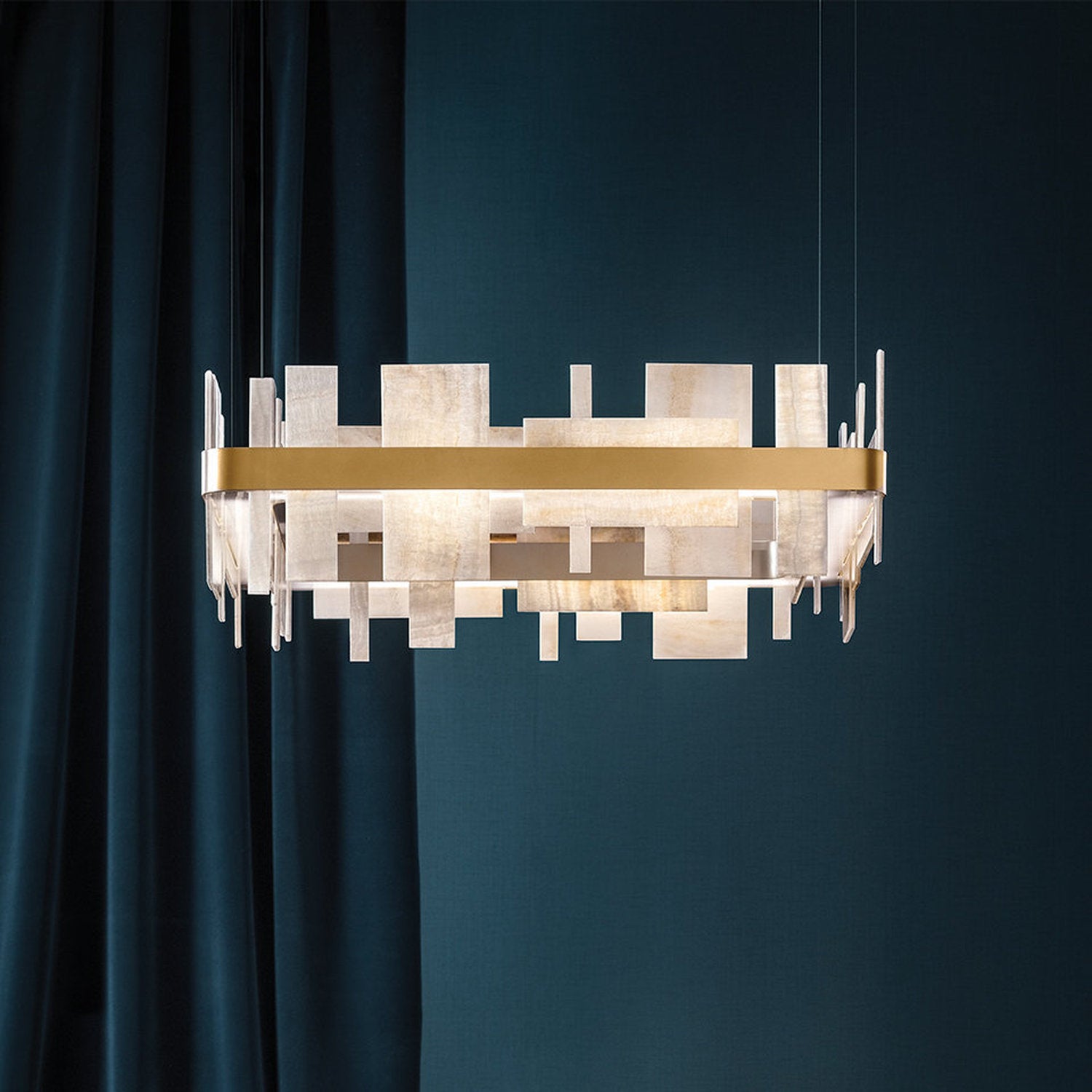 Lampadario a sospensione in ottone e lastre di onice, sospeso in un ambiente living con tende blu e pareti coordinate