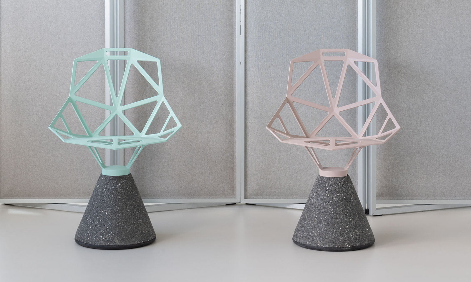 Due sedie Chair One Concrete Magis affiancate, una verde chiaro e una rosa, con base in cemento nero, su sfondo neutro