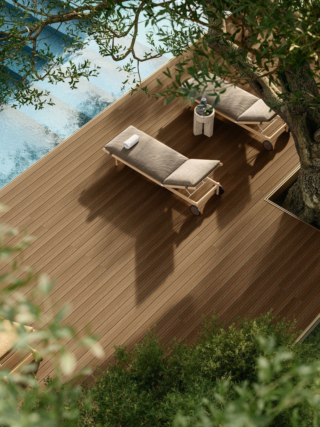 Decking Marina Pacto Skema in finitura chiara a bordo piscina, con lettini prendisole sotto un albero 