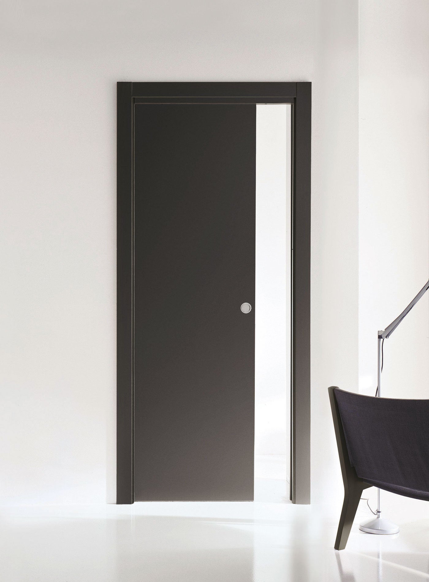 Porta scorrevole a scomparsa con finitura opaca e cornice minimale, installata in un ambiente living contemporaneo con arredi essenziali