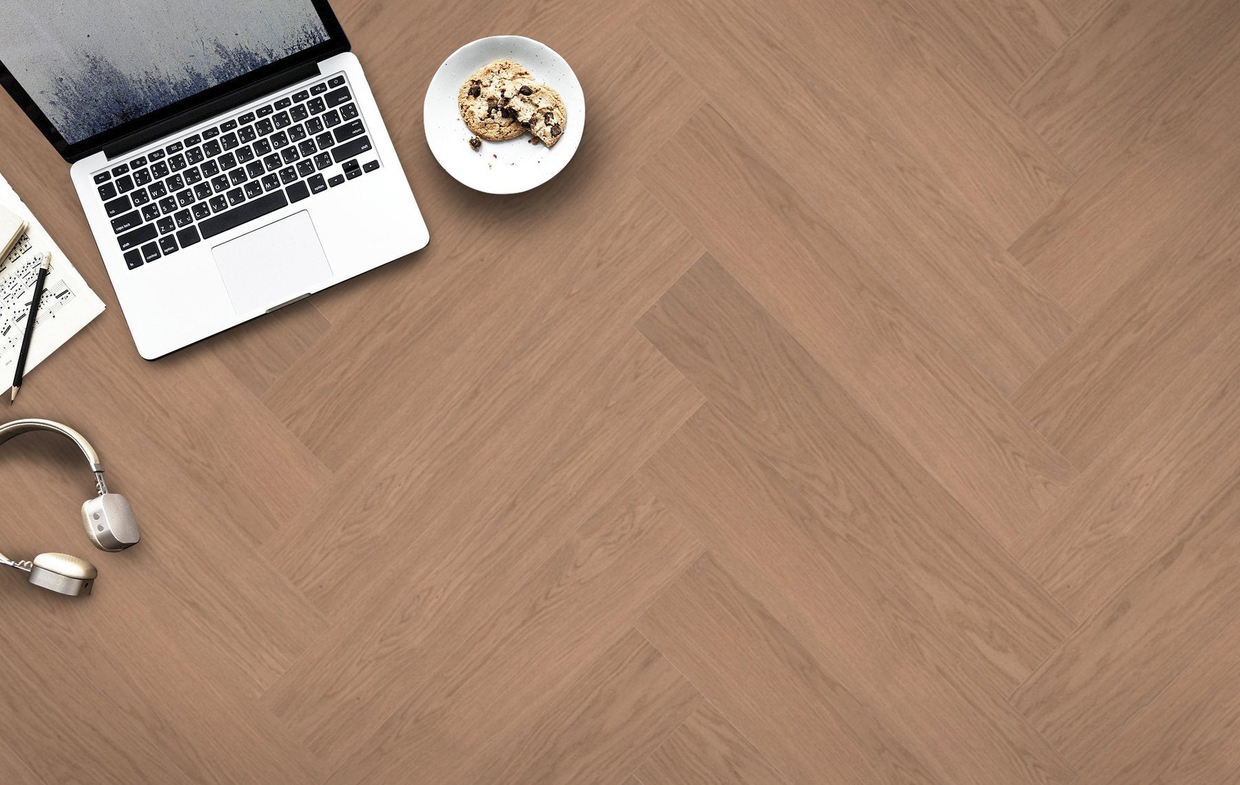 Laptop, cuffie e biscotti su pavimento Lumbertech S700 in Rovere Conero, posa a spina italiana con venatura regolare e tonalità calda.