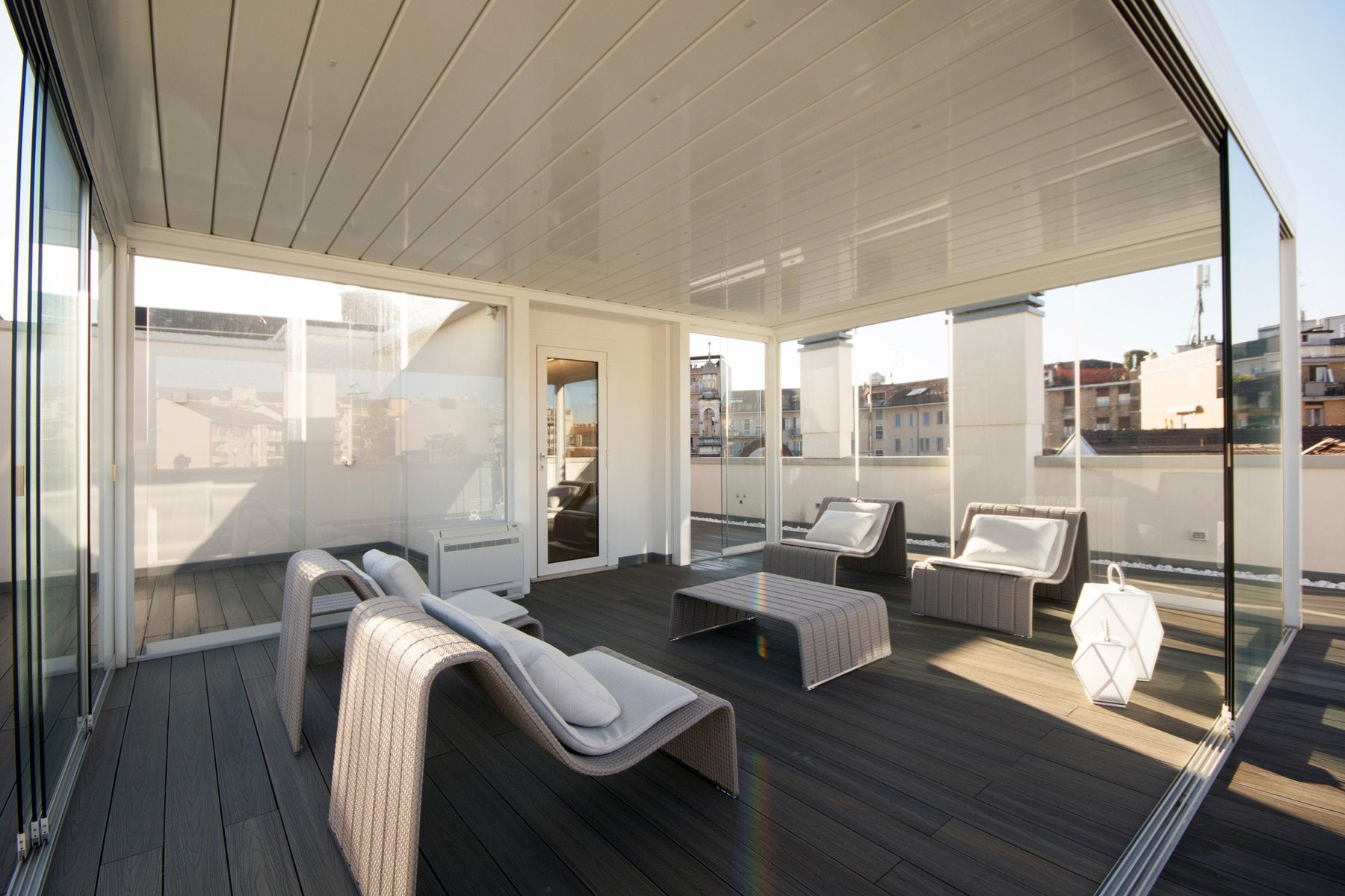 Decking in teak ossidato Skema su terrazzo coperto con sedute moderne e pareti vetrate