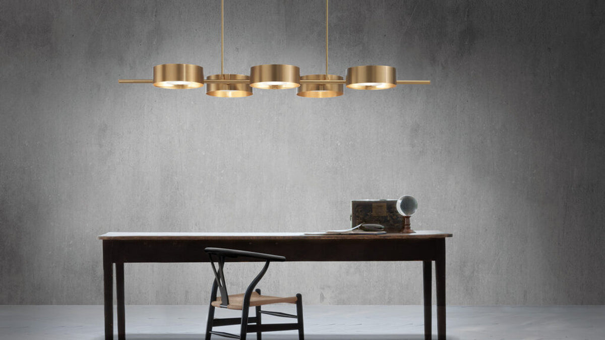 Lampadario a sospensione Sound BIL5 Masiero in oro spazzolato, con cinque diffusori circolari sopra un tavolo rettangolare.
