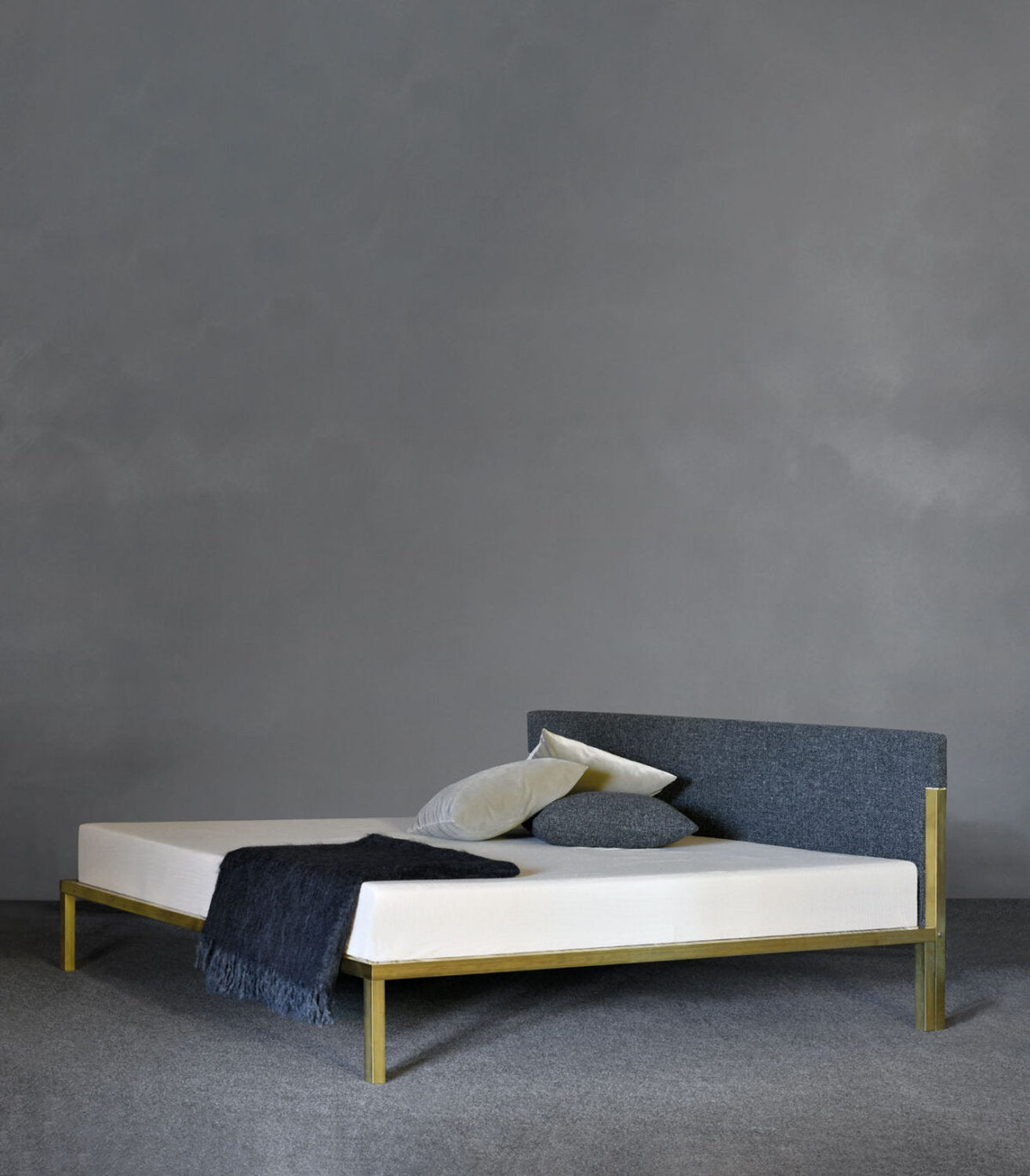 Letto design minimal di Xam in ottone con testiera imbottita in tessuto grigio