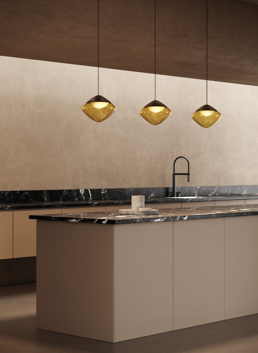 Tre lampade a sospensione Antesia Masiero in vetro ambra sopra l’isola di una cucina contemporanea.