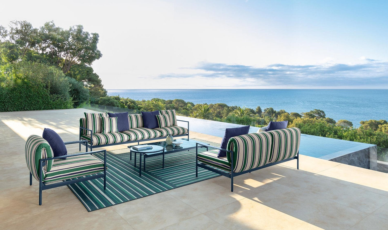 Collezione outdoor Talenti Nalu con divano, poltrone e tavolini a righe su terrazza con piscina