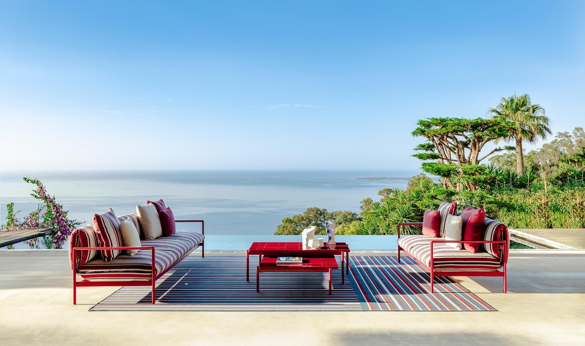 Divani outdoor Talenti Nalu a righe rosse con tavolini su terrazza panoramica vista mare