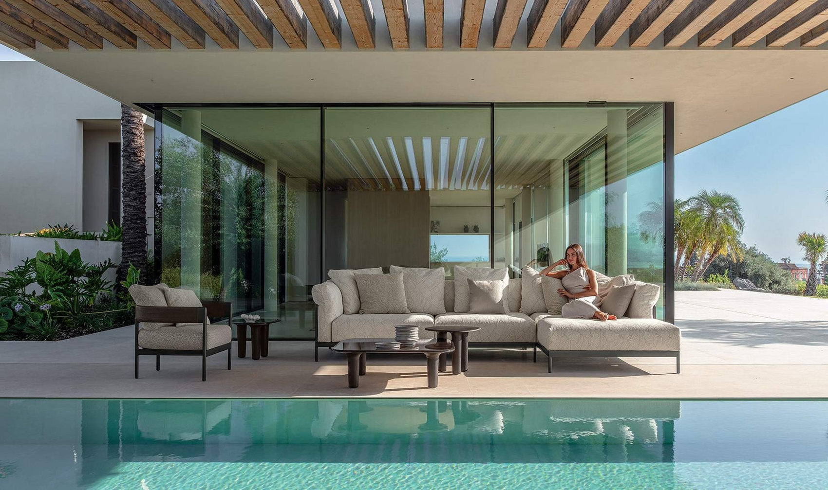 Arredo outdoor Talenti Flow con divano modulare in alluminio e teak in zona piscina