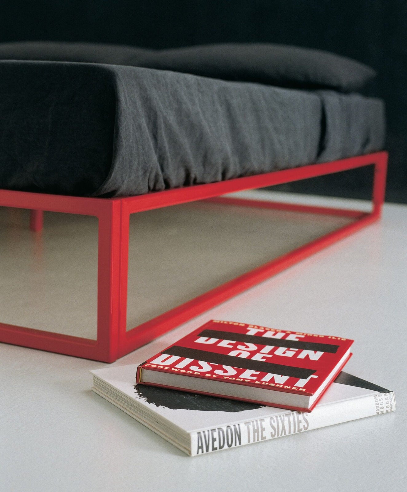 Dettaglio angolare del letto Asha Basic con struttura rossa e libri di design sul pavimento 