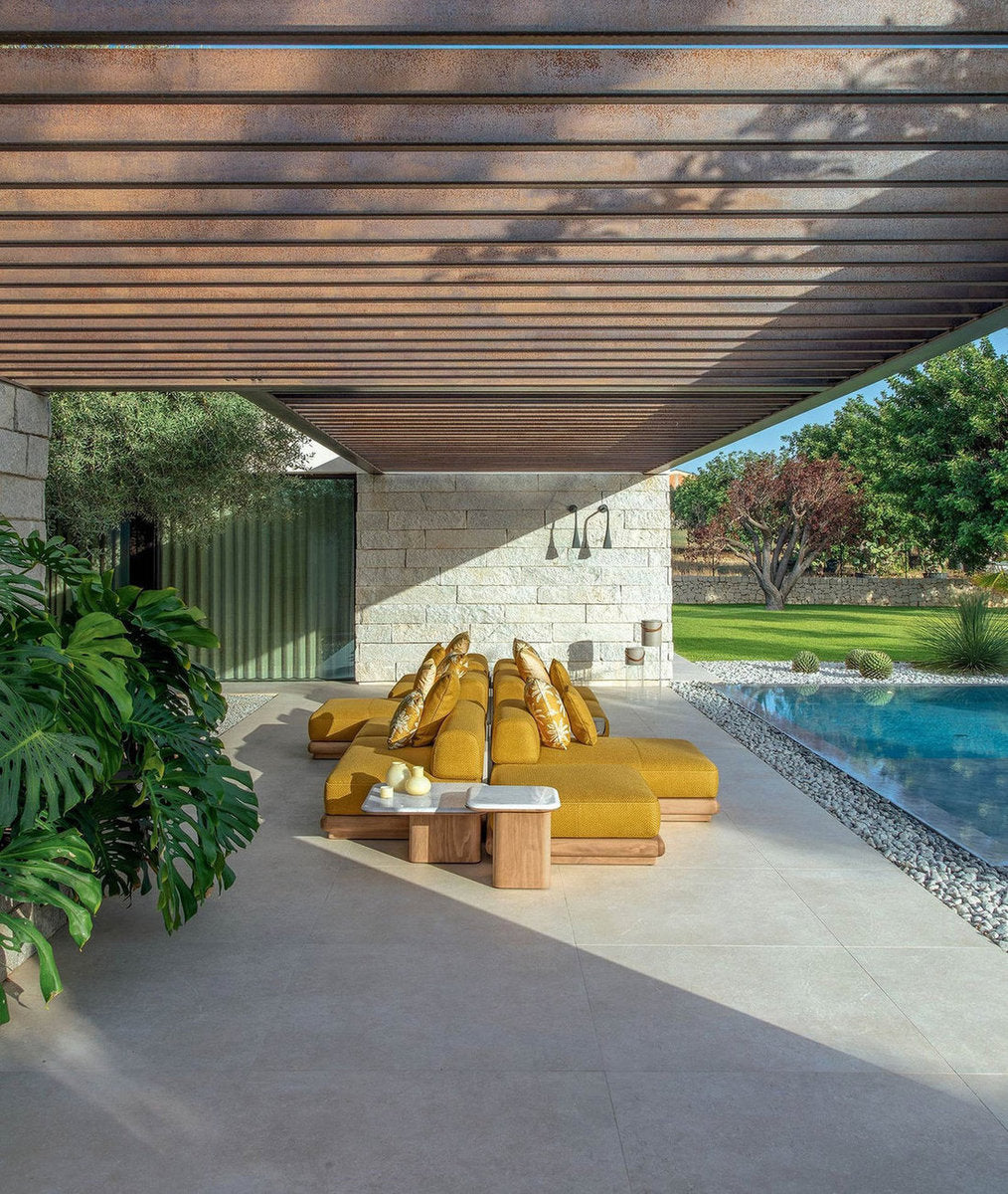 Divano modulare da esterno Itaca Talenti sotto pergola in patio con piscina e tavolini coordinati