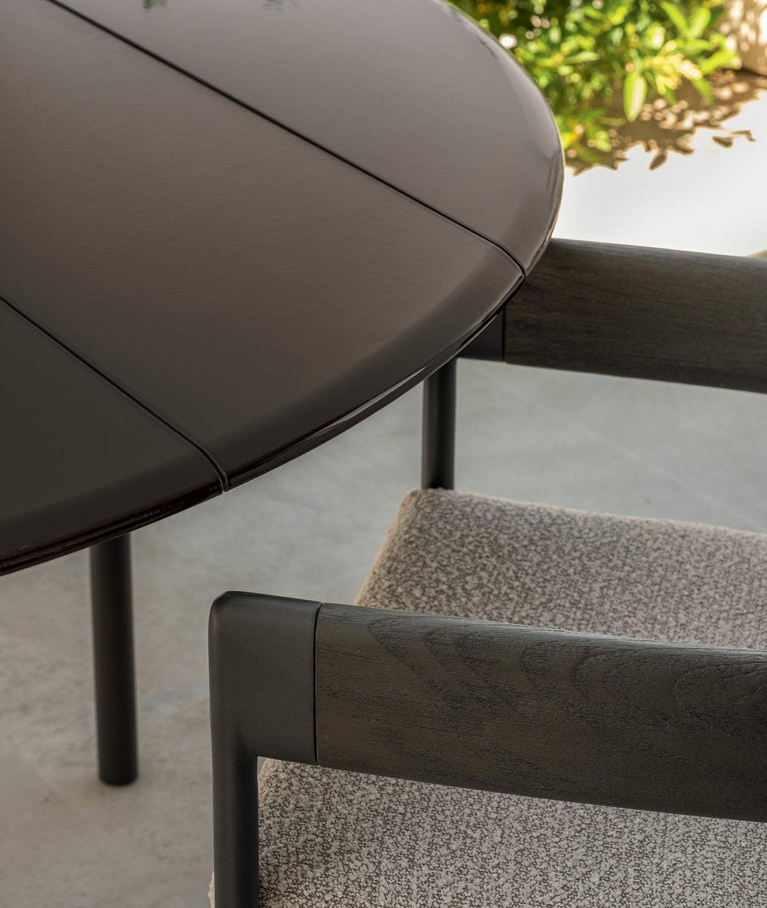 Dettaglio tavolo rotondo outdoor Flow Talenti con piano in gres e sedia con struttura in legno e tessuto