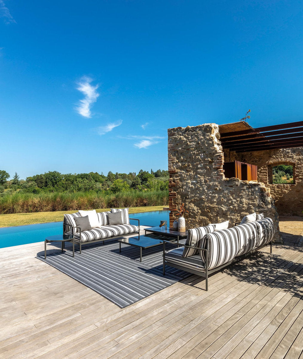 Divani per esterni Talenti Nalu a righe grigie con tavolini su deck in legno vicino alla piscina