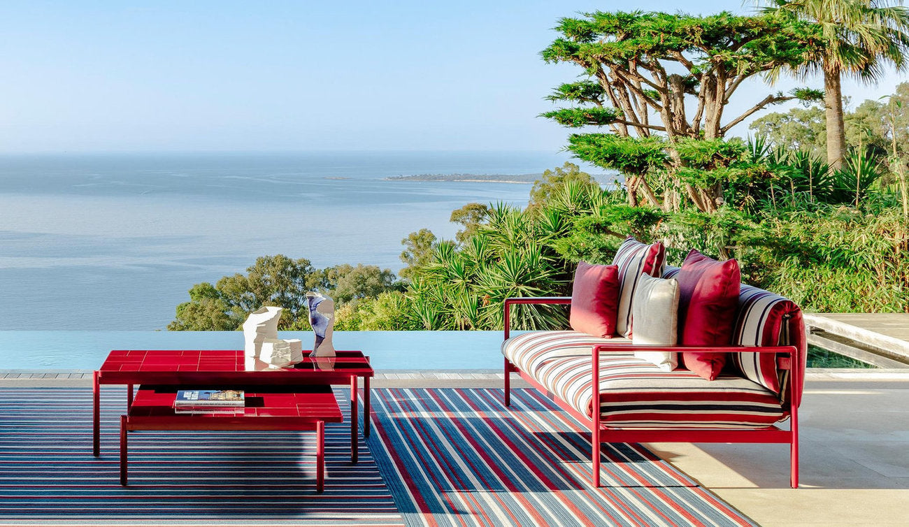 Divano outdoor Talenti Nalu a righe rosse con tavolino basso per terrazza vista mare