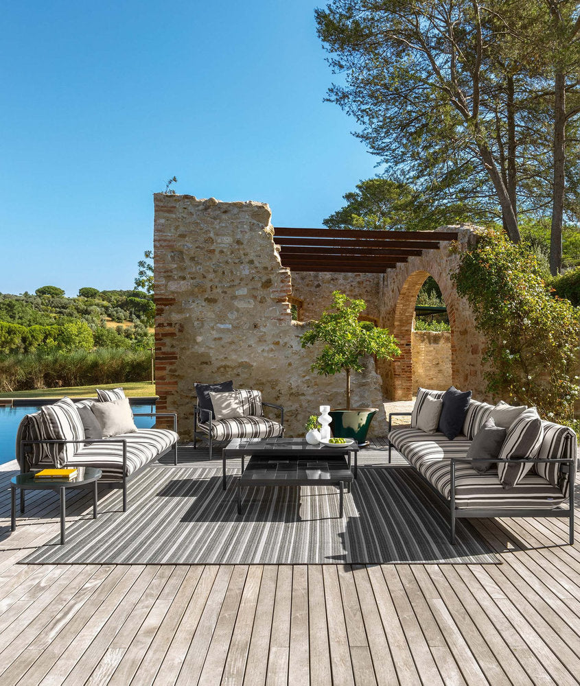 Living outdoor Talenti Nalu con divani a righe grigie e tavolini su terrazza con piscina