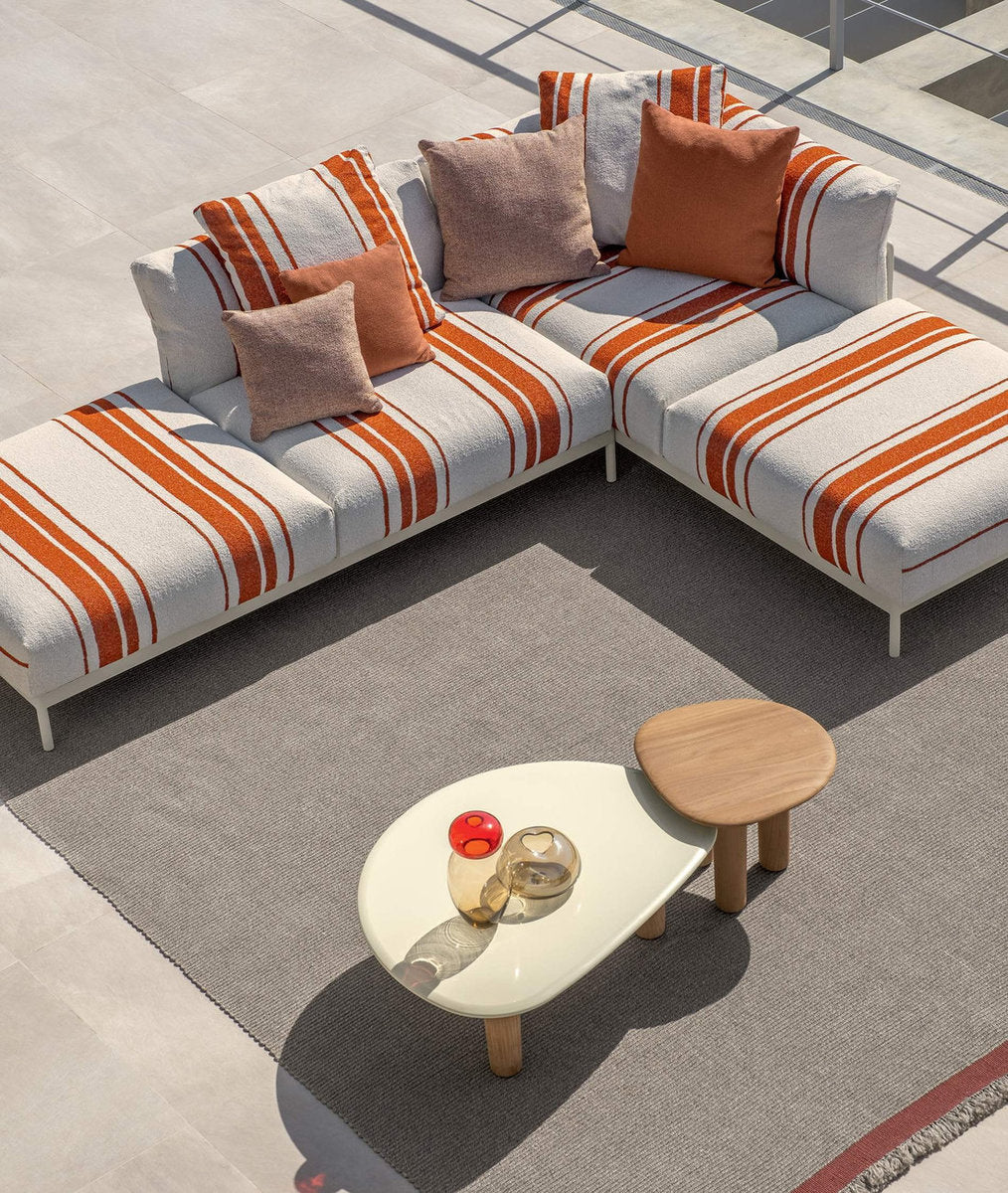 Divano da esterno Talenti Flow con tavolini in teak e piano in gres su terrazza panoramica